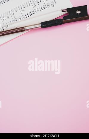 Nahaufnahme eines Geigenbogens mit Noten auf dem Pink Surface - Platz für Text Stockfoto
