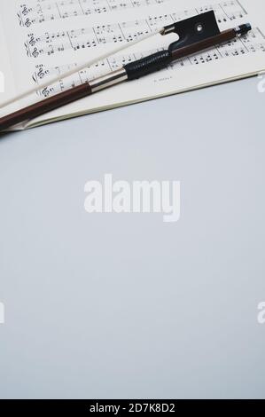 Nahaufnahme eines Geigenbogens mit Noten auf dem Graue Fläche - Platz für Text Stockfoto
