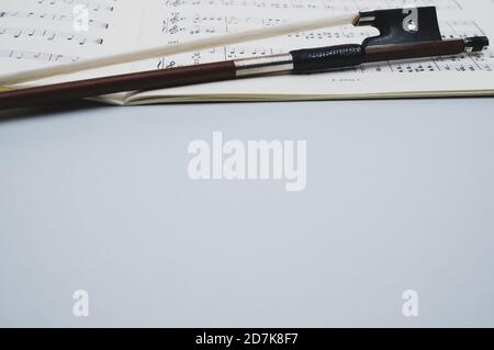 Nahaufnahme eines Geigenbogens mit Noten auf dem Graue Fläche - Platz für Text Stockfoto