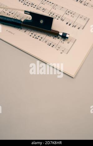 Nahaufnahme eines Geigenbogens mit Noten auf dem Graue Fläche - Platz für Text Stockfoto