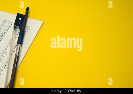 Nahaufnahme eines Geigenbogens mit Noten auf dem Gelbe Fläche - Platz für Text Stockfoto