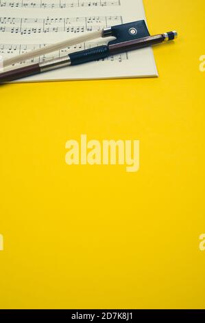 Nahaufnahme eines Geigenbogens mit Noten auf dem Gelbe Fläche - Platz für Text Stockfoto
