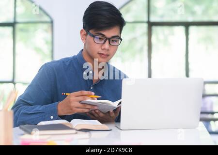 Junge collage Schüler mit Computer und mobilen Gerät online zu studieren. Bildung und online lernen. Stockfoto