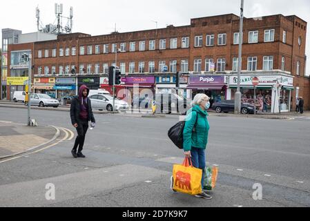 Slough, Großbritannien. Oktober 2020. Eine Frau trägt eine Gesichtsbedeckung, um die Ausbreitung des Coronavirus zu verhindern. Die Regierung hat angekündigt, dass Slough seinen COVID-Alarmstatus von Stufe 1 mittlere Warnung auf Stufe 2 hohe Warnung mit Wirkung von 00:01 Uhr am Samstag, dem 24. Oktober ändern wird, nachdem die COVID-19-Fälle anstiegen, was zu einer Infektionsrate von 153 Fällen pro 100,000 führt. Kredit: Mark Kerrison/Alamy Live Nachrichten Stockfoto