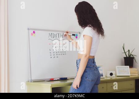 Frau, die auf einem Whiteboard schreibt, um die Aufgaben zu planen Stockfoto