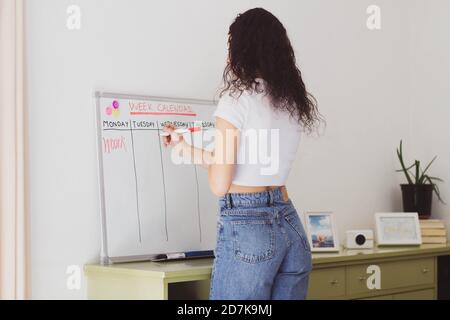 Frau, die auf einem Whiteboard schreibt, um die Aufgaben zu planen Stockfoto