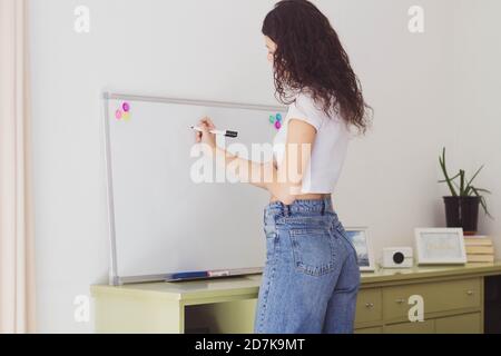 Frau, die auf einem Whiteboard schreibt, um die Aufgaben zu planen Stockfoto