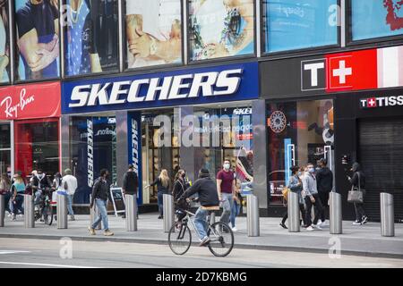Die Leute laufen am Broadway entlang im Times Square Viertel vorbei an einem Sketchers Laden in Manhattan, New York City. Stockfoto