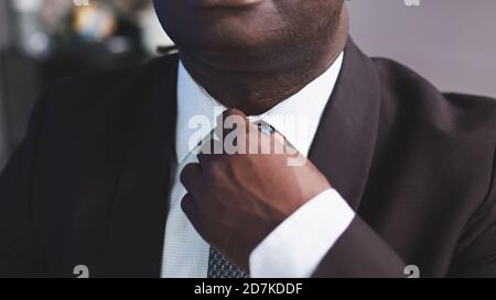Schöner afrikanischer Mann in einem Anzug, der die Krawatte anpasst. Hochwertige Fotos Stockfoto