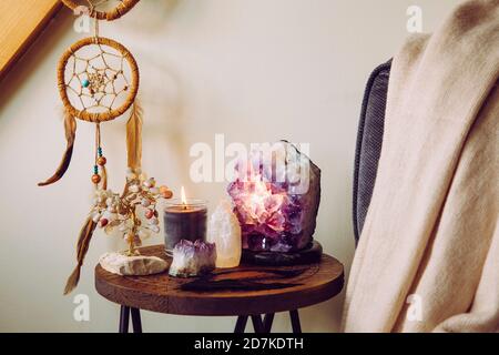 Entspannender Hausschrein mit entspannenden Objekten, Amethyst Cluster Geode Lampe beleuchtet, Duftkerze brennen, Selenit Turm Stein, Kristall Draht Baum. Stockfoto