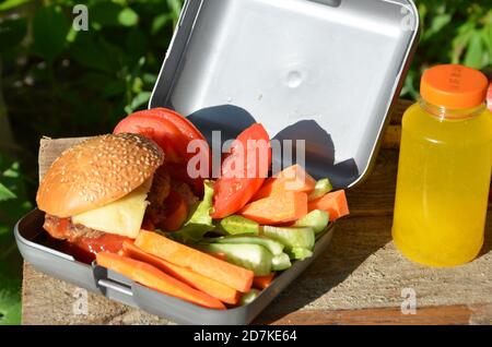 Lunch-Boxen mit Lebensmitteln bereit für die Arbeit oder die Schule, Mahlzeit Vorbereitung oder Diät-Konzept zu gehen. Hamburger mit Salat. Gelber Orangensaft. Mit Banane Stockfoto