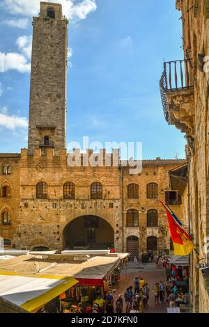 Erhöhter Blick auf die Piazza del Duomo mit dem Torre Rognosa und dem Palazzo Comunale Rathaus an einem Markttag mit Menschen, San Gimignano, Toskana, Italien Stockfoto