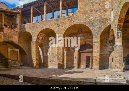 Innenhof des Palazzo Comunale Rathaus mit Touristen aufgereiht unter dem Vordach, um das Stadtmuseum, San Gimignano, Siena, Toskana, Italien zu betreten Stockfoto