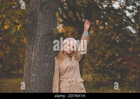 Junge schöne Frau im Herbst, die auf Hallo verzichtet und im Freien lächelt, freundliche Willkommensgeste Stockfoto