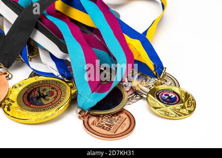 Viele glänzende Sportmedaillen auf verschiedenen bunten Bändern isoliert auf weißem Hintergrund. Flache horizontale Ansicht. Stockfoto