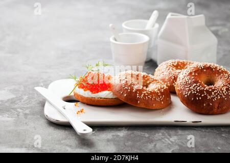 Frische hausgemachte Bagels-Sandwiches mit Frischkäse und rotem Kaviar auf Keramik-Servierbrett, selektiver Fokus Stockfoto