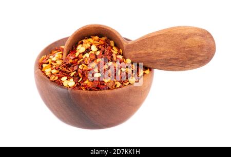 Chili und Paprika in Holzschüssel und Löffel, isoliert auf weißem Hintergrund. Mischen Sie die scharfe und süße Paprika mit Körnern. Stockfoto