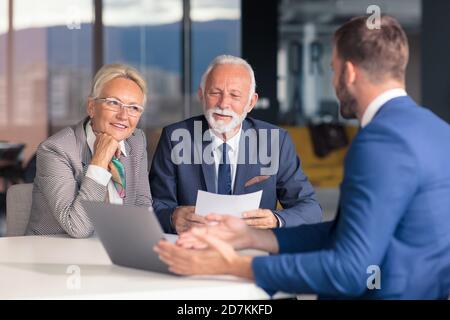 Positiv gealtertes Paar, das mit Versicherungsagent berät Stockfoto