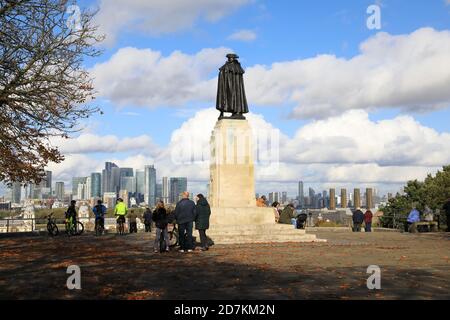 Neben der Statue von General James Wolfe sehen die Menschen die Ansicht von der Spitze des Greenwich Park, in Richtung Canary Wharf, im Herbst, SE London, Großbritannien Stockfoto