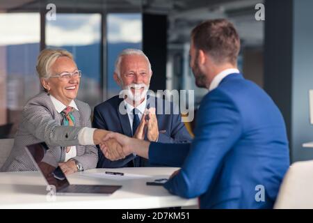 Positiv gealtertes Paar, das mit Versicherungsagent berät Stockfoto