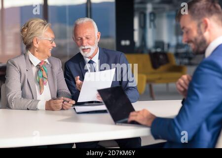 Positiv gealtertes Paar, das mit Versicherungsagent berät Stockfoto