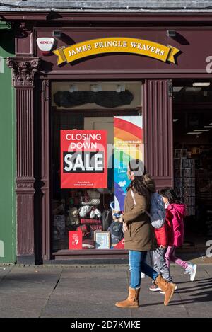 Frau mit Kindern geht an einem Schild "Closing Down Sale" auf James Pringle Weavers vorbei, im Besitz von Edinburgh Woolen Mill, an der Royal Mile, Edinburgh. Stockfoto