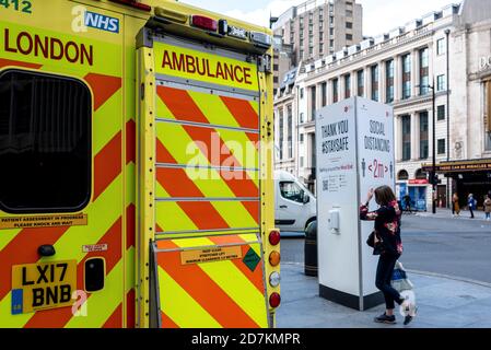 London, Vereinigtes Königreich- Oktober 22 2020: Social Distancing Sign im Hintergrund mit der Rückseite eines UK Ambulance geparkt daneben. London ist... Stockfoto