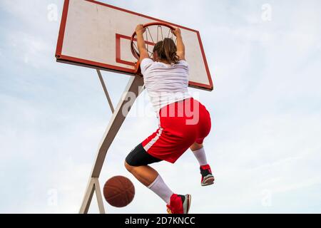 Frauen spielen Basketball auf dem Straßenplatz. Frau Streetball-Spieler machen Slam Dunk in einem Basketballspiel. Stockfoto