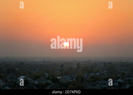 Sonnenuntergang über der nebligen Stadt, Häuser. Stadt bei warmem Sonnenuntergang Stockfoto