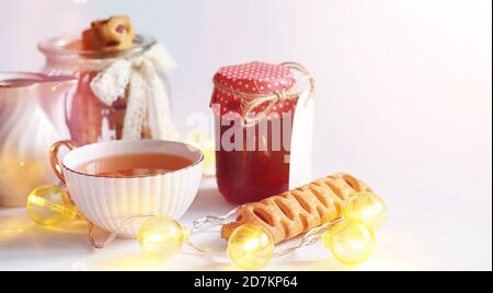 Tee mit Gebäck zum Frühstück. Süßigkeiten und Gebäck mit Nüssen für Tee auf weißem Hintergrund. Eine Kaffeetasse und Patties. Stockfoto