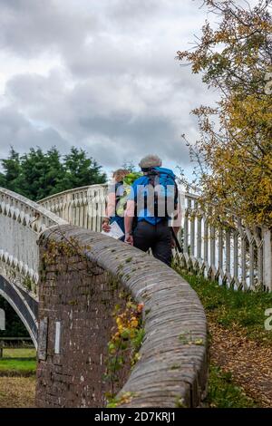 Ein Mann und eine Frau, die auf dem Treidelpfad über eine Brücke auf dem Grand Union Kanal in Braunston, daventry, northamptonshire, großbritannien, wandern Stockfoto