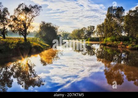 Spiegelung der Sonne in ruhigen stillen Gewässern des Macquarie Flusses bei Sonnenaufgang in Dubbo Stadt von Australien. Stockfoto