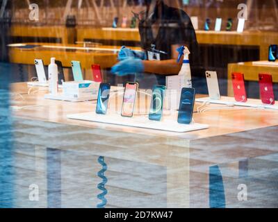 Paris, Frankreich - 23. Okt 2020: Silhouette der Arbeiterinnen Reinigung mit Alkohol Handgel Desinfektionsmittel das neue iPhone 12 und iPhone 12 Pro wird während des Einführungstages im Apple Store ausgestellt. Die neuesten 5G-Smartphones sind weltweit erhältlich. Stockfoto