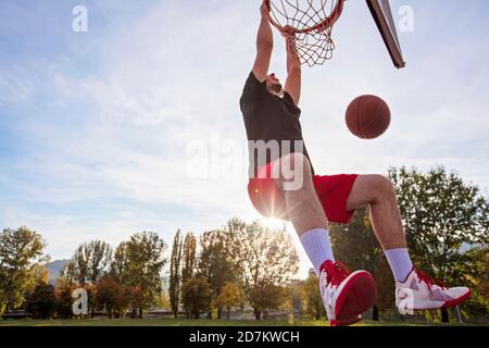 Junger Mann springen und eine fantastische Slam Dunk Streetball, Basketball zu spielen. Urbane verbindlich. Stockfoto