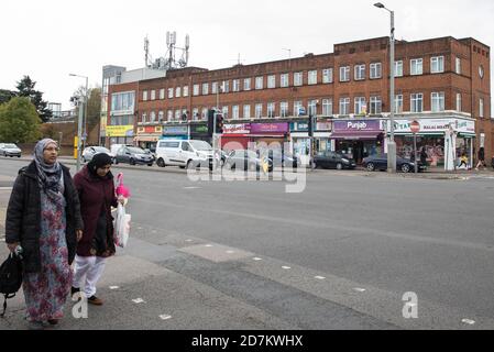 Slough, Großbritannien. Oktober 2020. Zwei Frauen gehen vor einer Parade von Geschäften in der Farnham Road. Die Regierung hat angekündigt, dass Slough seinen COVID-Alarmstatus von Stufe 1 mittlere Warnung auf Stufe 2 hohe Warnung mit Wirkung von 00:01 Uhr am Samstag, dem 24. Oktober ändern wird, nachdem die COVID-19-Fälle anstiegen, was zu einer Infektionsrate von 153 Fällen pro 100,000 führt. Kredit: Mark Kerrison/Alamy Live Nachrichten Stockfoto