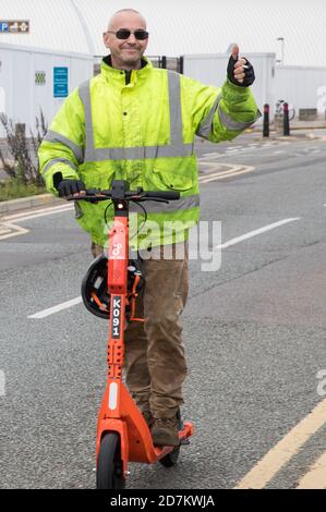 Slough, Großbritannien. Oktober 2020. Ein Mann fährt einen orangefarbenen Neurone Mobility E-Scooter. Neuron Mobility hat in Slough einen Mietversuch gestartet, bei dem die Bewohner 250 E-Scooter mit einer Smartphone-App mieten und diese im Bus und auf den Straßen des Stadtteils fahren können, jedoch nicht auf Gehwegen, einschließlich Gehwegen. Kredit: Mark Kerrison/Alamy Live Nachrichten Stockfoto