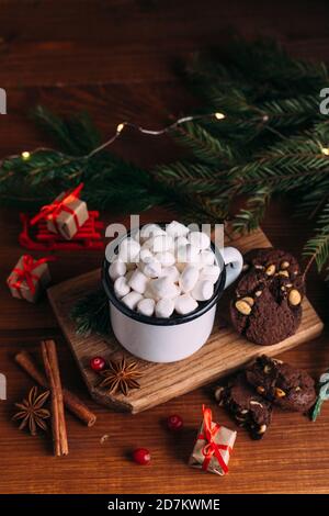 Emaillierte Tasse heißen Kakao oder Kaffee mit Marshmallows und Keksen. Tannenzweige und weihnachtsgeschenke. Stockfoto
