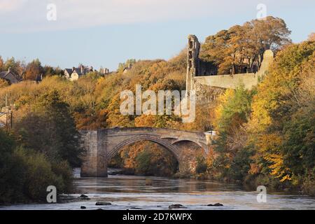 Der Fluss Tees fließt unter der County Bridge mit den Ruinen von Barnard Castle beleuchtet von späten Abendlicht im Herbst, Teesdale, County Durham, Stockfoto