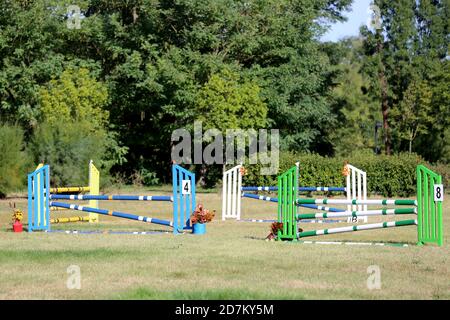 Buntes Bild von Springpfosten in einer Open-Air-Springarena. Hindernisse Pole Barrieren für springende Pferde als Hintergrund Stockfoto