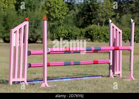 Buntes Bild von Springpfosten in einer Open-Air-Springarena. Hindernisse Pole Barrieren für springende Pferde als Hintergrund Stockfoto