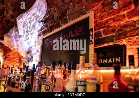 Warendorf, Deutschland. Oktober 2020. Über der Bar #One in Warendorf, neben zahlreichen Flaschen alkoholischer Getränke, befindet sich eine Tafel mit der Aufschrift: 'Sperrstunde 23:00 Uhr'. Nordrhein-Westfalen hat in allen Gemeinden mit hohen Neuinfektionen eine obligatorische Ausgangssperre zwischen 23.00 und 6.00 Stunden für die Gastronomie eingeführt. Die Ausgangssperre gilt in Gemeinden mit 50 oder mehr Neuinfektionen pro 100,000 Einwohner innerhalb von sieben Tagen. Quelle: Guido Kirchner/dpa/Alamy Live News Stockfoto