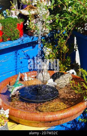 Ein kleiner solarbetriebener Wasserbrunnen ist Teil einer Besonderheit In einem Märchengarten Stockfoto