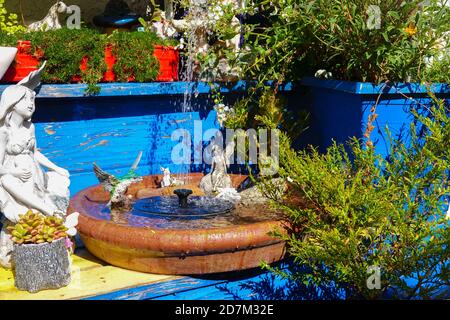 Ein kleiner solarbetriebener Wasserbrunnen ist Teil einer Besonderheit In einem Märchengarten Stockfoto