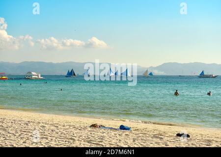 Boracay, Philippinen - 29. Januar 2020: Weißer Strand der Insel Boracay. Touristen gehen am Strand entlang und schwimmen im Meer. Einige Tage vor dem Ausbruch Stockfoto