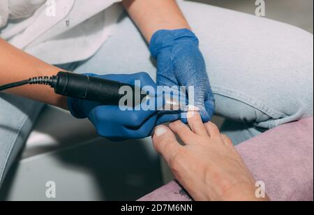 Pediküre Prozess im Salon. Fußpflege Behandlung und Nagel. Der Prozess der professionellen Pediküre. Master in blauen Handschuhen macht Pediküre mit Maniküre mac Stockfoto