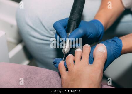 Pediküre Prozess im Salon. Fußpflege Behandlung und Nagel. Der Prozess der professionellen Pediküre. Master in blauen Handschuhen macht Pediküre mit Maniküre mac Stockfoto