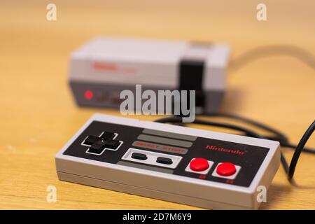 Der Controller eines Nintendo Entertainment System Classic Edition wird auf einem Holzboden in die Konsole eingesteckt und in die Konsole eingesteckt. Stockfoto