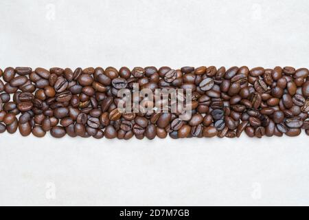 Braune Kaffeebohnen auf dem Hintergrund der hellen Textur Recycling-Öko-Papier. Zentrale horizontale Position Objekte, kopieren Platz für Text oben und bot Stockfoto