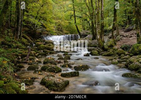 Ein schöner Gebirgsbach mit kleinem Wasserfall im Herbstwald Querformat Stockfoto