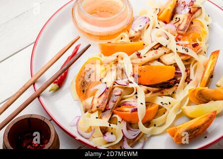 Orientalisches Essen, Salat mit Nudeln, Kaki und Auberginen. Leckerer Makkaroni-Salat Stockfoto